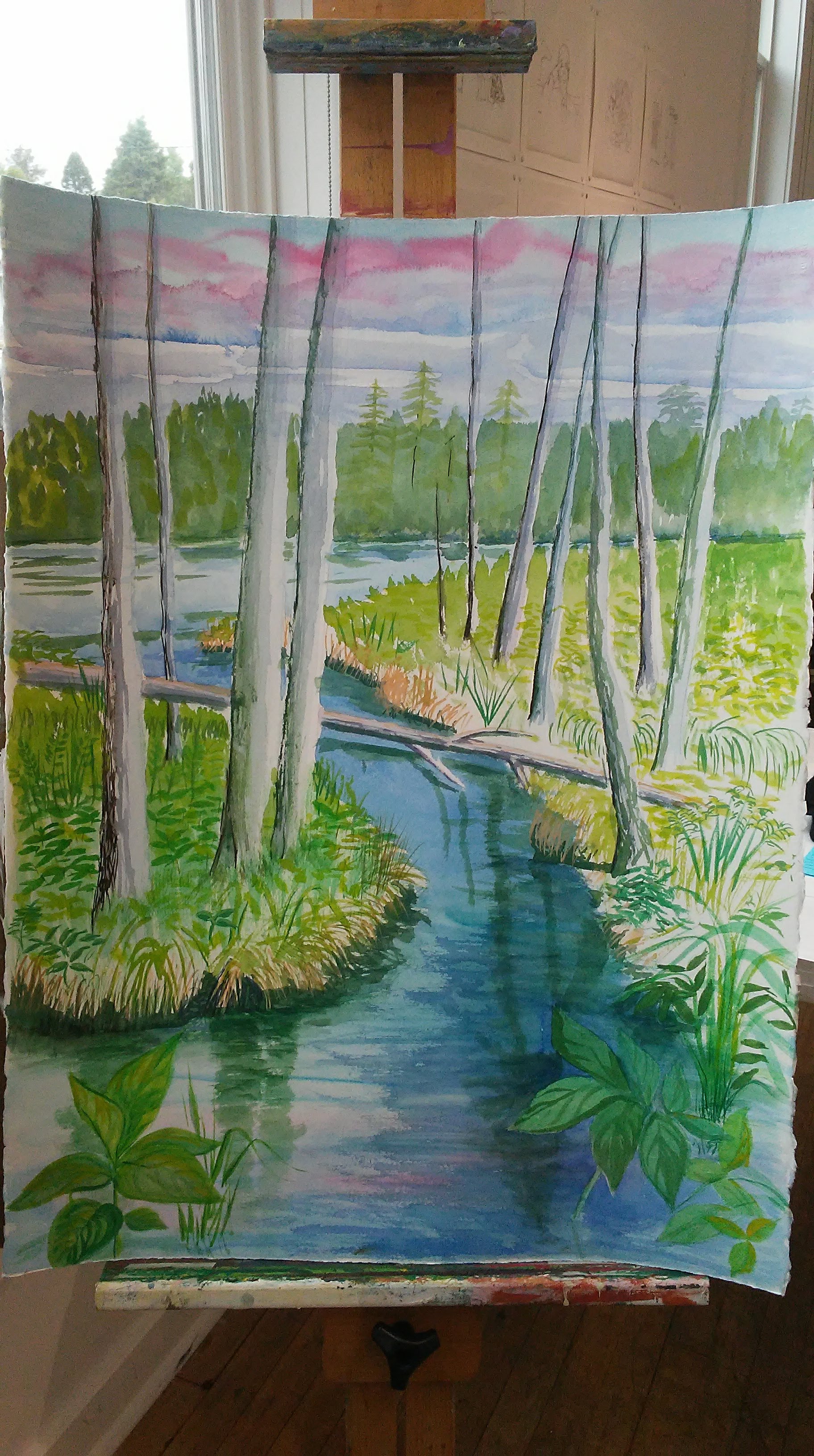 Painting of water and trees on an easel
