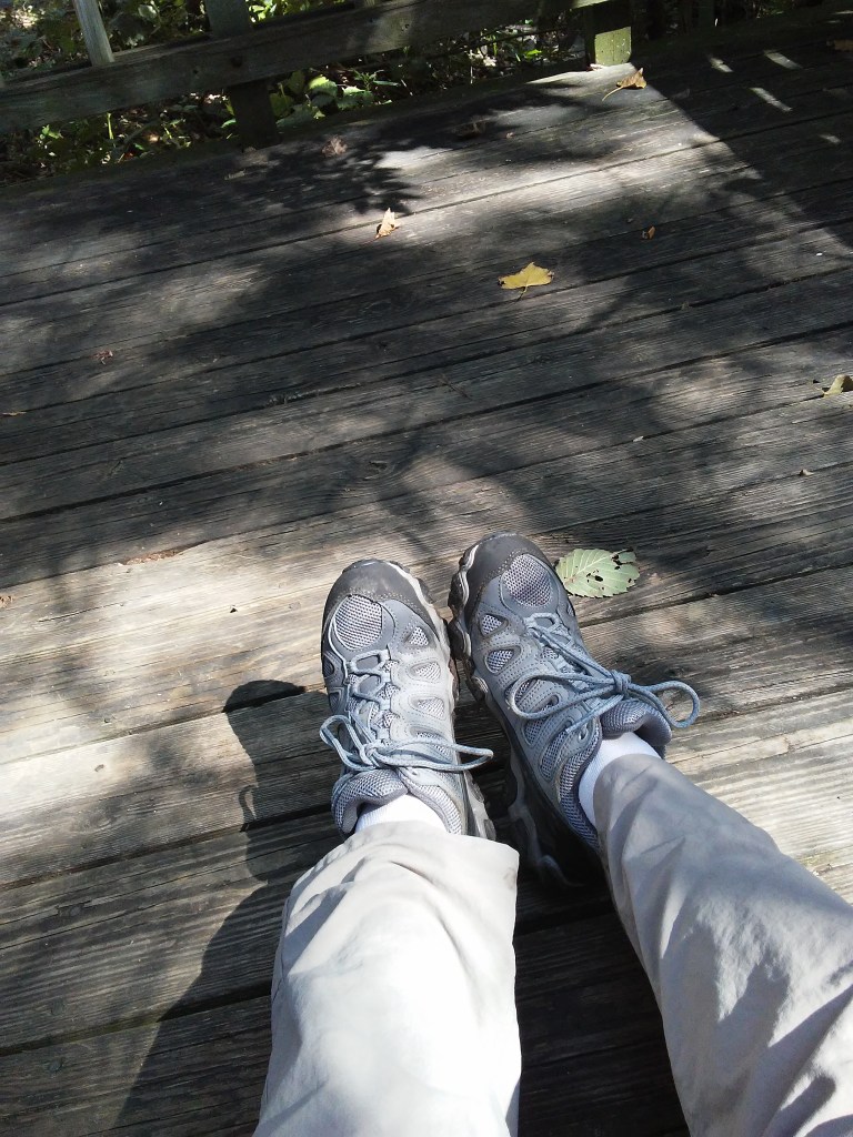 feet in grey athletic shoes on a wood deck.