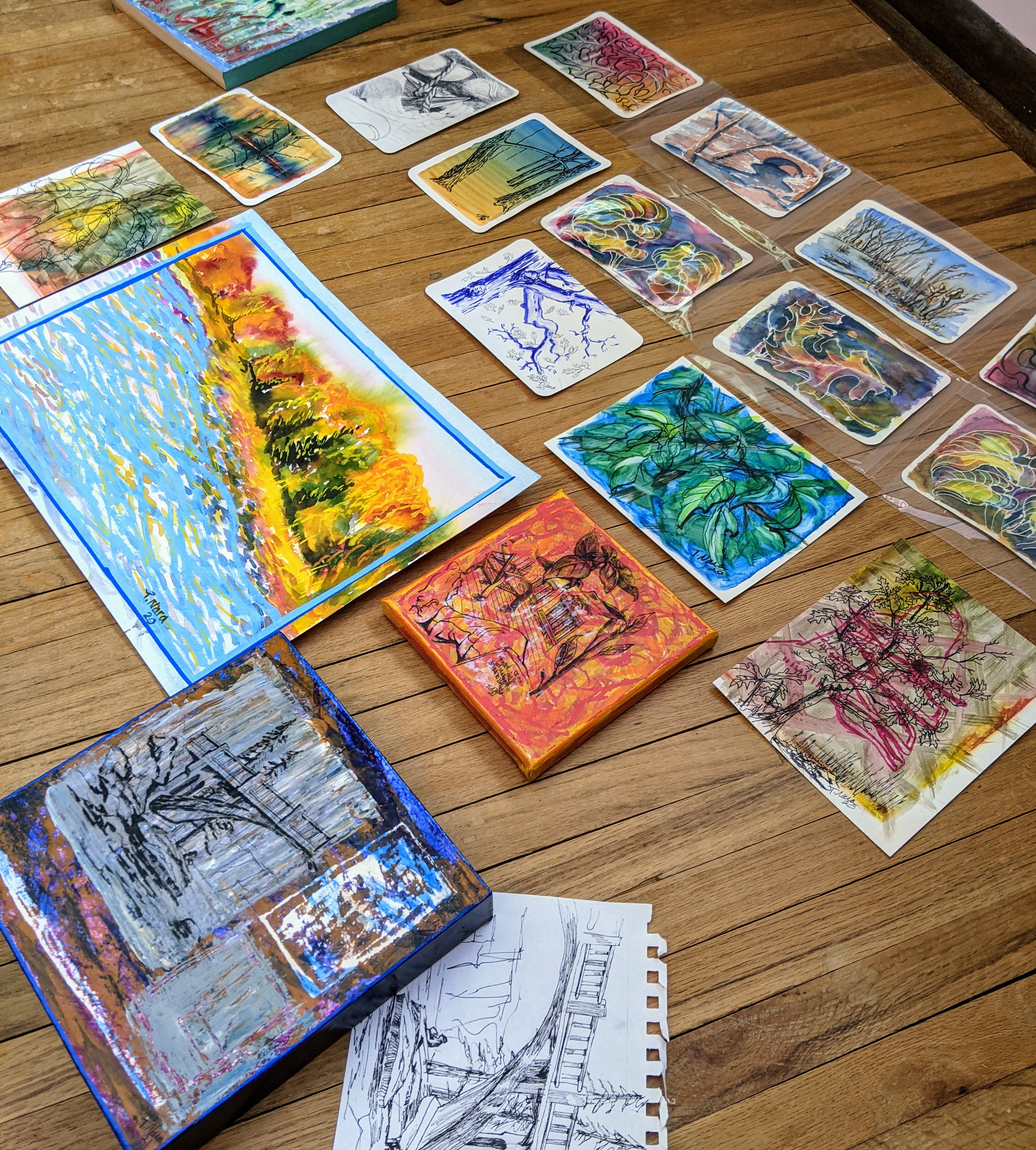 lots of paintings laid out on a wood floor