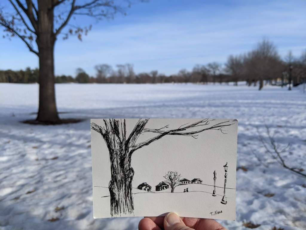 a sketch held in front of a winter landscape