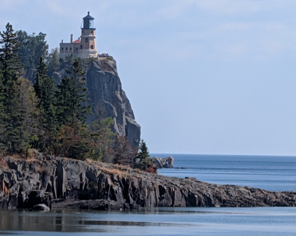 photo of Split Rock lighthouse showing cliff and triangular lower rocks. Lake Superior horizon